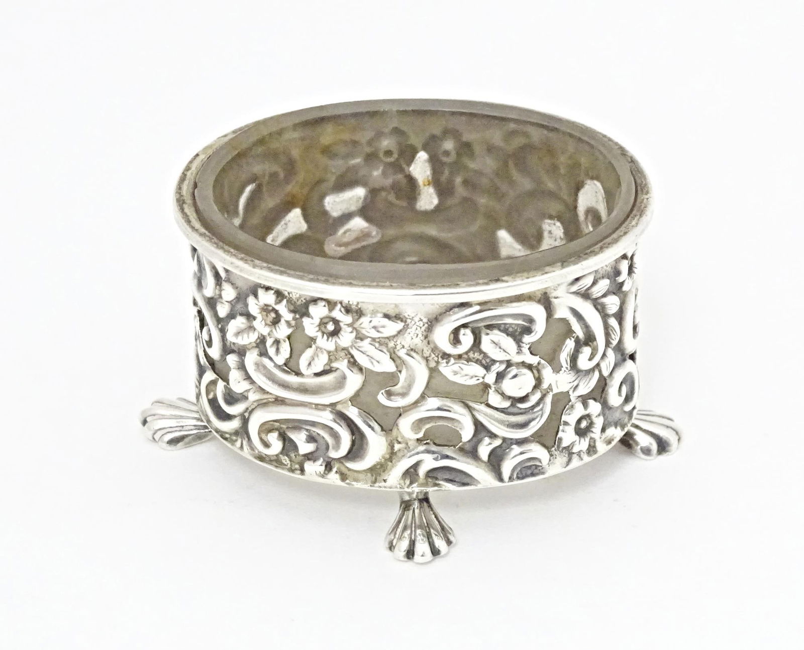 A Victorian silver salt of oval form with embossed decoration and four stylised paw feet, and clear (1 of 7)
