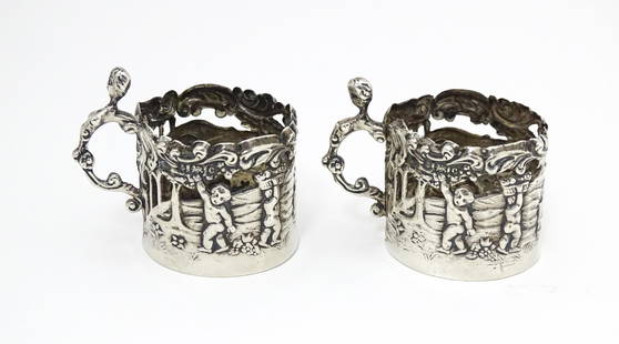 A pair of miniature silver cup sleeves / tot glass holders with embossed and pierced decoration,: A pair of miniature silver cup sleeves / tot glass holders with embossed and pierced decoration, hallmarked Birmingham 1902 maker William Comyns & Sons Ltd . Approx. 1 1/2" high (2)Please Note - we do