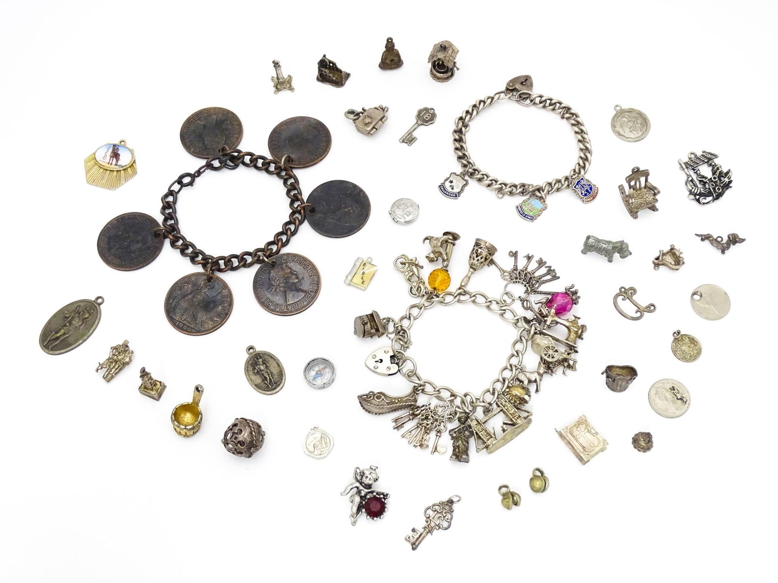 Two silver and white metal charm bracelets set with assorted charms. Together with a quantity of: Two silver and white metal charm bracelets set with assorted charms. Together with a quantity of various charms, pendants, etc. and a bracelet set with Queen Elizabeth II one penny coins.Please Note -
