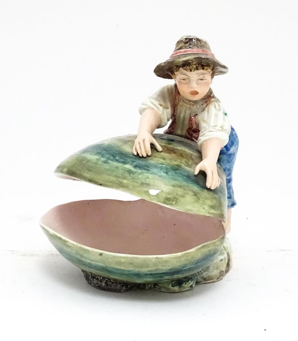 A Continental majolica style dish modelled as a boy with a large shell. Impressed under 416. Approx.: A Continental majolica style dish modelled as a boy with a large shell. Impressed under 416. Approx. 7" highPlease Note - we do not make reference to the condition of lots within descriptions. We are