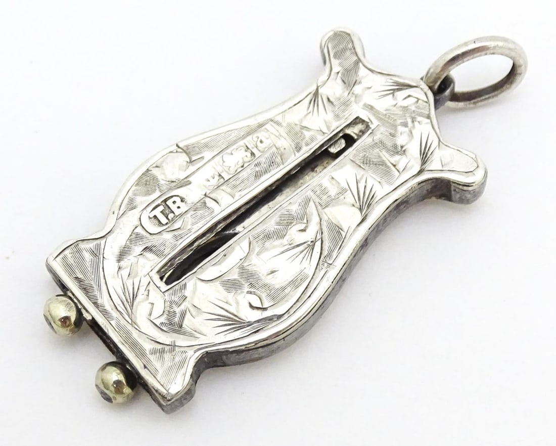 A silver cigar / cheroot cutter of stylised lyre form with engraved acanthus scroll detail: A silver cigar / cheroot cutter of stylised lyre form with engraved acanthus scroll detail hallmarked Birmingham 1900 maker T Beardsmore. Approx. 1 1/4" (closed)Please Note - we do not make reference 