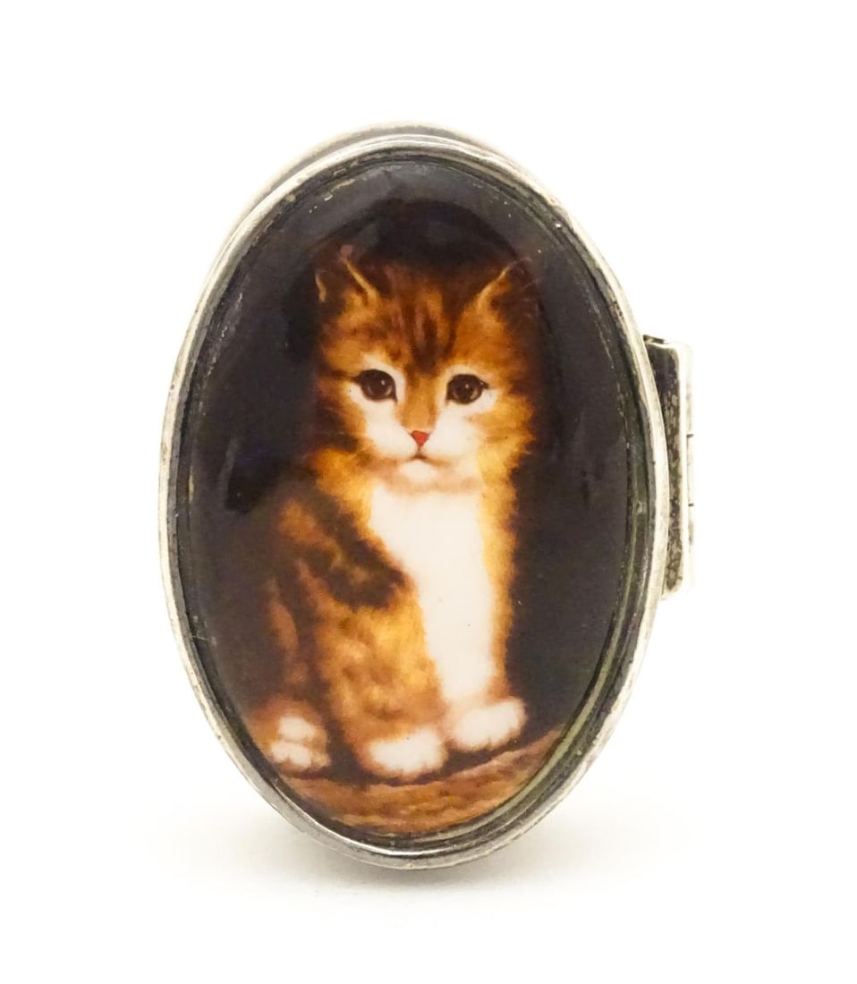 A silver pill box with cabochon to top decorated with a cat / kitten. Approx. 1 1/2" long Please: A silver pill box with cabochon to top decorated with a cat / kitten. Approx. 1 1/2" longPlease Note - we do not make reference to the condition of lots within descriptions. We are however happy to pr
