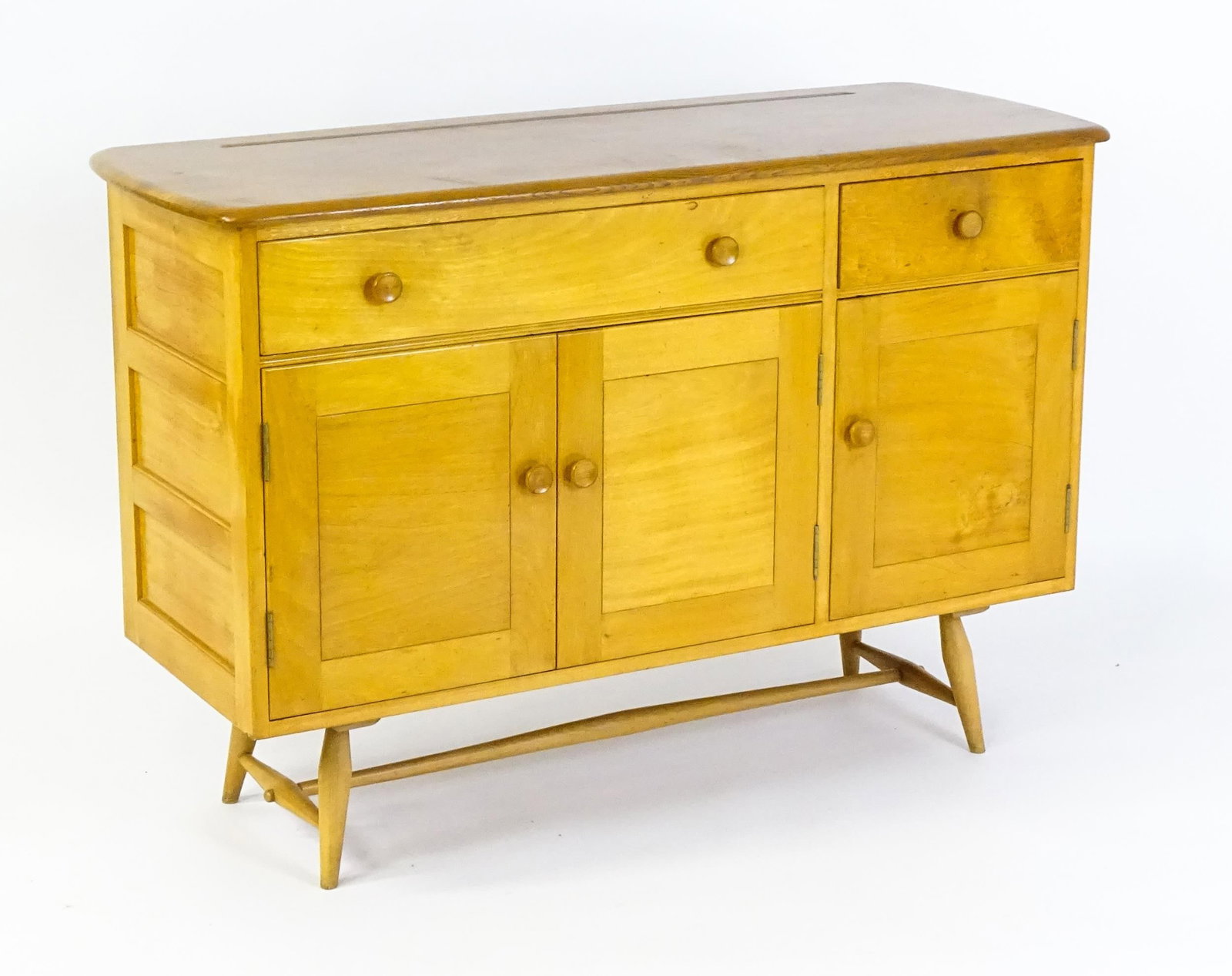 Vintage / Retro: An Ercol elm sideboard, model 351. The figured elm top above a single long drawer,: Vintage / Retro: An Ercol elm sideboard, model 351. The figured elm top above a single long drawer, short drawer and two cupboards to the base, the super structure raised on four tapering legs united