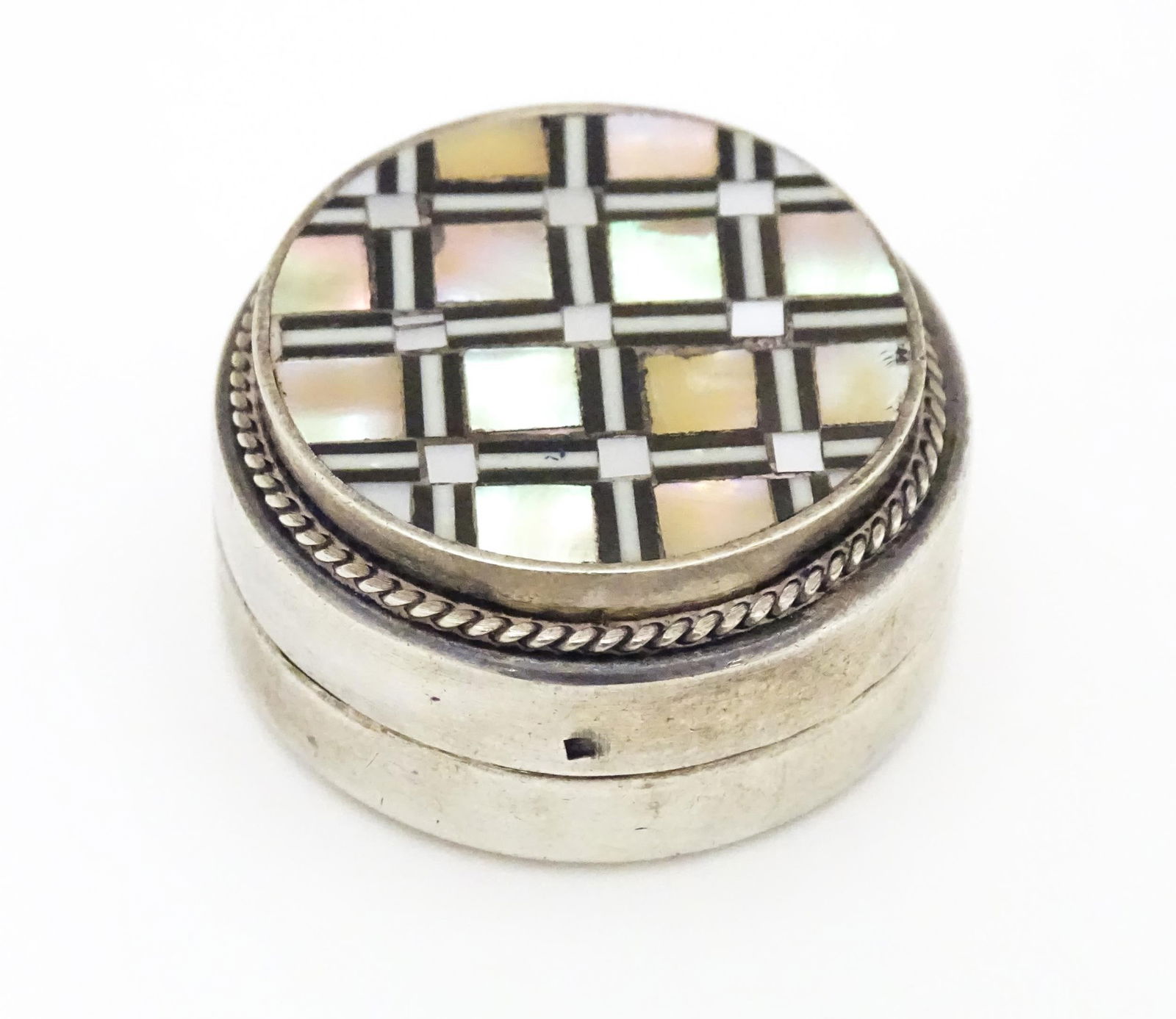 An Egyptian white metal pill box set with onyx and mother of pearl detail. 1/4" diameter Please: An Egyptian white metal pill box set with onyx and mother of pearl detail. 1/4" diameter Please Note - we do not make reference to the condition of lots within descriptions. We are however happy to pr