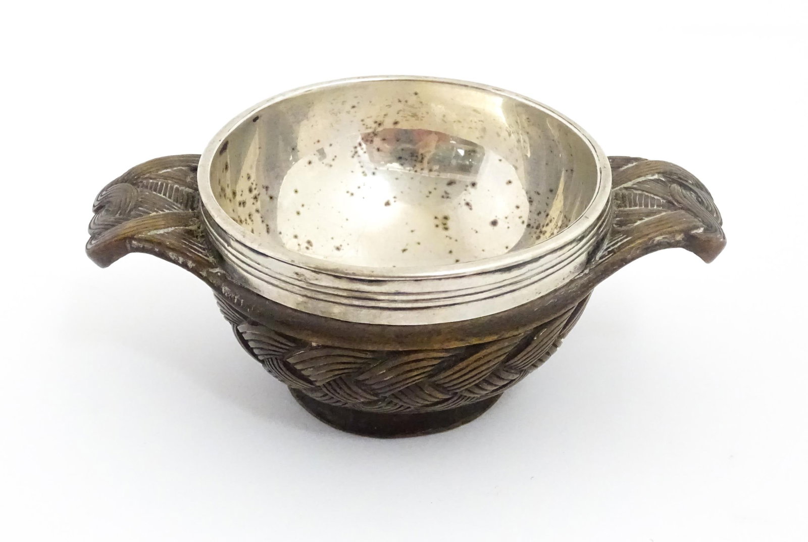 A 19thC Scottish carved wood quaich with plait style detail, the base with engraved floral motif bor: A 19thC Scottish carved wood quaich with plait style detail, the base with engraved floral motif bordered by the motto 'Thoir As I Mo Charaid', the white metal bowl with engraved stag head armorial ti