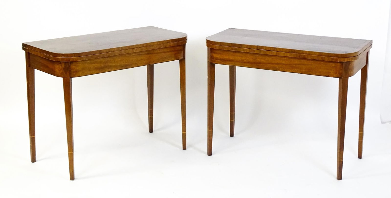A pair of Regency mahogany tea tables, both with hinged and rotating crossbanded tops raised on four: A pair of Regency mahogany tea tables, both with hinged and rotating crossbanded tops raised on four inlaid, tapering legs. 36" wide x 17 1/2" deep x 29" high. Please Note - we do not make reference t