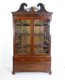 A George II / George III low waisted bookcase with an impressive swans neck architectural pediment: A George II / George III low waisted bookcase with an impressive swans neck architectural pediment with blind fretwork carving above two astragal glazed doors and a base comprising two short over one