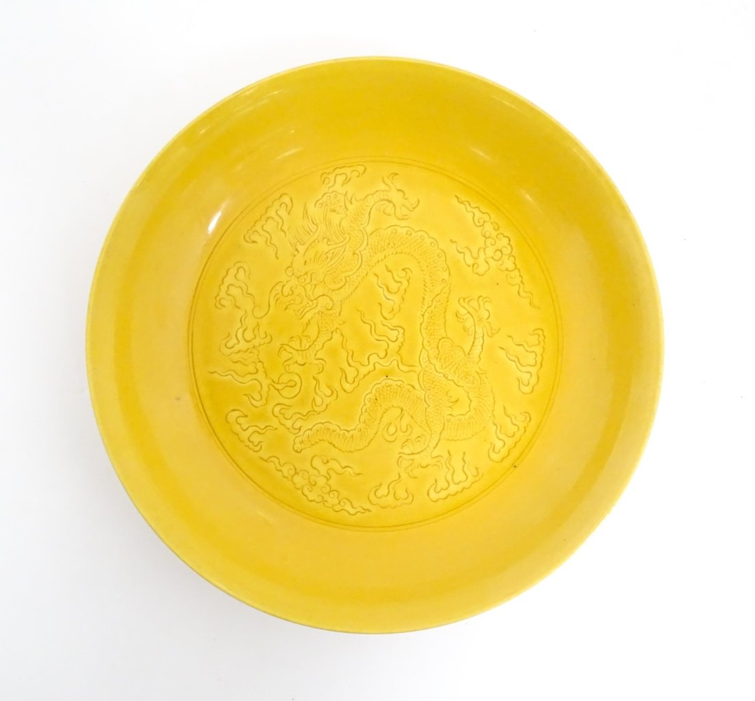 A Chinese dish with a yellow ground decorated with dragons amongst stylised clouds. Character marks: A Chinese dish with a yellow ground decorated with dragons amongst stylised clouds. Character marks under. Approx. 7 1/2" diameter Please Note - we do not make reference to the condition of lots withi