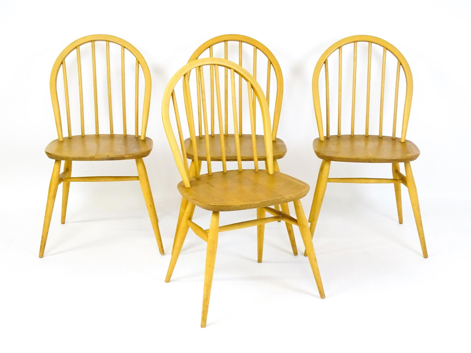 Vintage / Retro: A set of four elm seated Ercol dining chairs with hoop backs and raised on turned: Vintage / Retro: A set of four elm seated Ercol dining chairs with hoop backs and raised on turned tapering legs united by H - stretchers. 16 1/2" wide x 16" deep x 32" high.Please Note - we do not ma