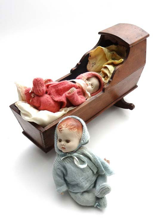 A 19thC wooden doll's cradle on rockers, with two mid 2: A 19thC wooden doll's cradle on rockers, with two mid 20thC plastic dolls . Cradle approximately 15 3/4" long. (3)