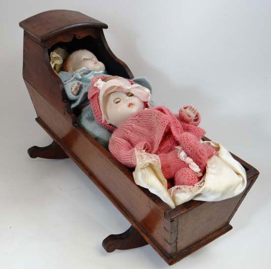 A 19thC wooden doll's cradle on rockers, with two mid 2: A 19thC wooden doll's cradle on rockers, with two mid 20thC plastic dolls . Cradle approximately 15 3/4" long. (3)