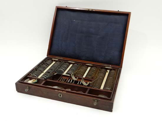 Optical : A mahogany cased opticians glasses eye testin: Optical : A mahogany cased opticians glasses eye testing set, containing Concave Cyl. Concave and convex and Cyl convex lens 18 1/2" wide