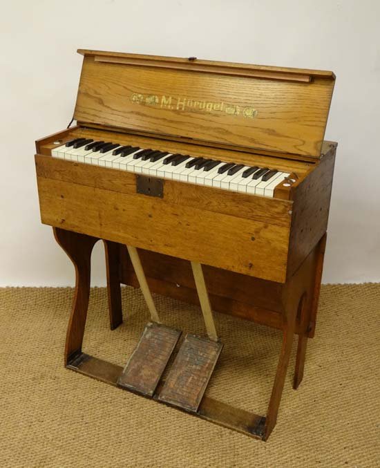Musical Instruments : A pine travel harmonium organ,: Musical Instruments : A pine travel harmonium organ, manufactured by M. Horugel of Leipzig. The pine body housing manual bellows and the four-octave keyboard, having levers for Flute & Viola effects,