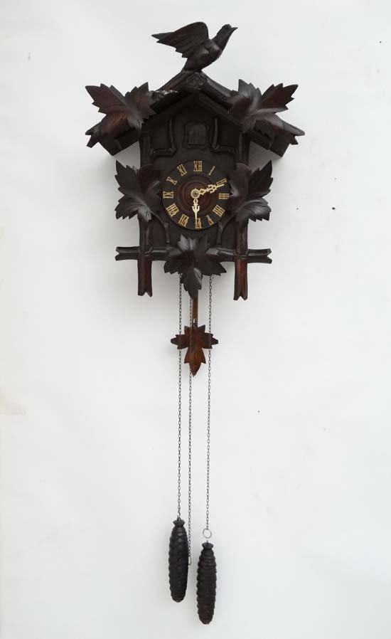 Black Forest Cuckoo Clock : a two weight Cuckoo clock: Black Forest Cuckoo Clock : a two weight Cuckoo clock with composite hands and cuckoo ( with two bellows) and wooden covered pendulum, side doors, the clock approximately 18" high. £40 - 60