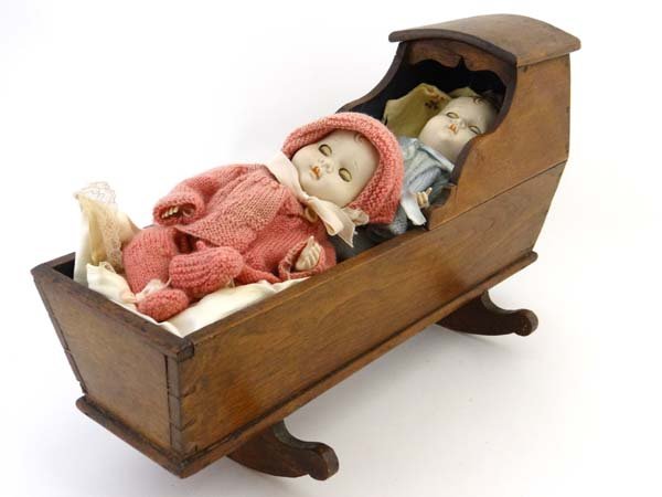 A 19thC wooden doll's cradle on rockers, with two mid: A 19thC wooden doll's cradle on rockers, with two mid 20thC plastic dolls . Cradle approximately 15 3/4" long. (3) Please Note - Prospective purchasers must satisfy themselves as to the condition of l