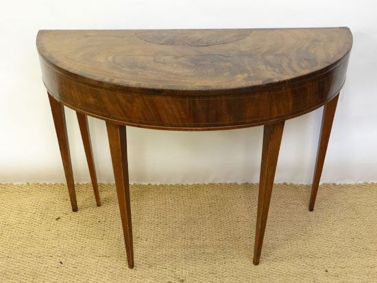 A Regency mahogany demi-lune fold over games / card: A Regency mahogany demi-lune fold over games / card table with green baize lining and single hinged fifth leg. 39" wide