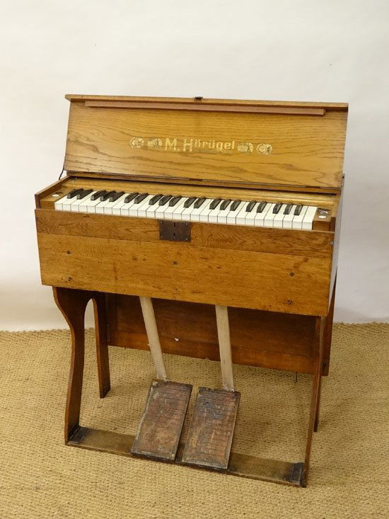 Musical Instruments : A pine travel harmonium organ,: Musical Instruments : A pine travel harmonium organ, manufactured by M. Horugel of Leipzig. The pine body housing manual bellows and the four-octave keyboard, having levers for Flute & Viola effects,