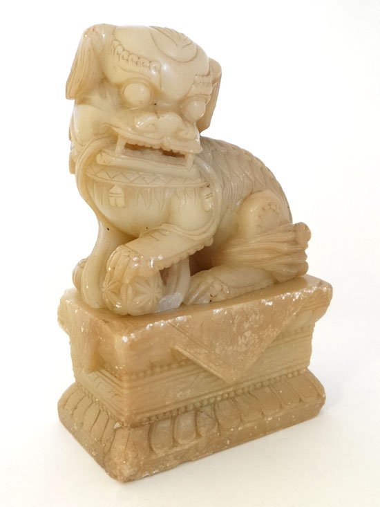 A Chinese Jade Dog of Fo with paw upon a pearl of: A Chinese Jade Dog of Fo with paw upon a pearl of wisdom, mounted upon a plinth, standing 9 1/2" high