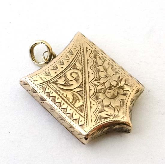 A late 19thC/early 20thC gilt metal shield shaped: A late 19thC/early 20thC gilt metal shield shaped locket with engraved decoration 1" high Please Note - Prospective purchasers must satisfy themselves as to the condition of lots prior to bidding £40