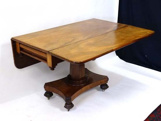 A Victorian mahogany drop leaf breakfast table of: A Victorian mahogany drop leaf breakfast table of squared form and held by hexagonal tapering column / pedestal on a shaped base and 4 cup covered castors. Has drawer to one end. 47 1/4" wide x 47" lo