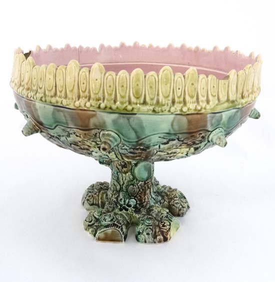 A 19thC large Majolica pedestal bowl. The base in the: A 19thC large Majolica pedestal bowl. The base in the form of a tree stump with green relief decoration and pink interior. c1900. 10'' high. 12 1/2'' diameter. Please Note - we do not make reference t
