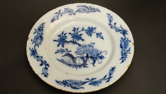 An 18thC Delft plate painted in blue with Chinoiserie: An 18thC Delft plate painted in blue with Chinoiserie floral design with trailing foliate sprays to border. Diameter 9"