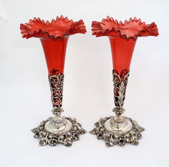 A pair of 20thC silver plate and cranberry glass: A pair of 20thC silver plate and cranberry glass centrepiece epergne, the cast silver plated base with single cranberry glass flute with flared rim. Each approx 14 3/4" high. £200 - 300