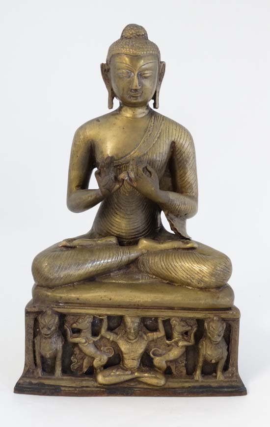 A c1900 brass Nepal / India seated teaching Budda upon: A c1900 brass Nepal / India seated teaching Budda upon a base supported by cross legged figure and 4 dogs. 15'' high. £80 - 120
