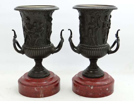 Claude Michel Clodion (1738-1814), A pair of Patinated: Claude Michel Clodion (1738-1814), A pair of Patinated bronze campana urns depicting classical figures in relief and standing on turned rouge marble bases with gilt interiors. Each signed. 13" high