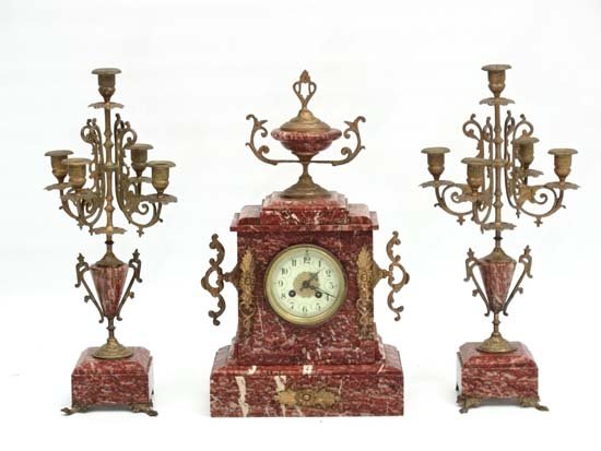 Rose Marble French Mantle clock and Garnitures : a: Rose Marble French Mantle clock and Garnitures : a Marble cased and urn mounted clock with a pair of 5 branch candelabra garnitures, the dial with Arabic numeral hours and minute markers , the 8 day c