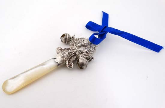 A childs rattle with embossed image to centre depicting (1 of 4)