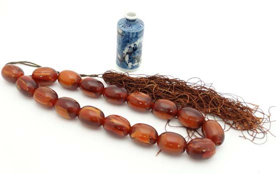 A Chinese blue and white snuff bottle of cylinder form: A Chinese blue and white snuff bottle of cylinder form , decorated with figures in a cave and in fields. 3'' high. Together with a amber coloured bead necklace with tassel detail. Approx 30'' long. (2