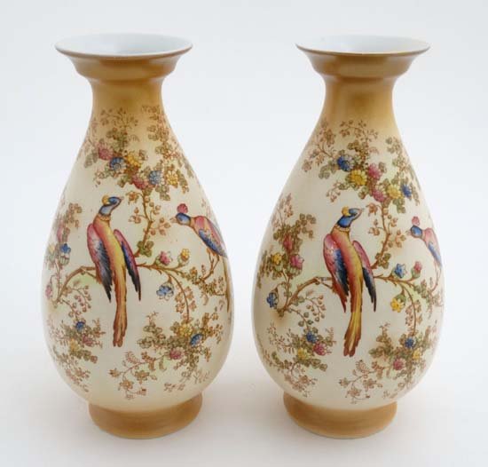 A pair of early 20thC A G R and Co ltd, Crown Ducal: A pair of early 20thC A G R and Co ltd, Crown Ducal ware blush ivory vases, decorated with birds and butterflies amongst flowering boughs, each bears factory stamp to base. 11 1/2'' high.