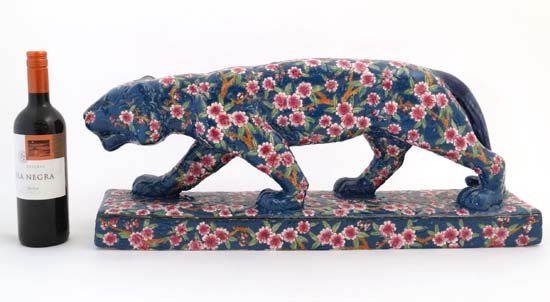 A late 20thC Longwy style French pottery figure of a: A late 20thC Longwy style French pottery figure of a panther / leopard, marked under '' Les Bleus de Louviere '' , number A400-F, decorated in enamels with pink and white flowers on a blue ground. 11 