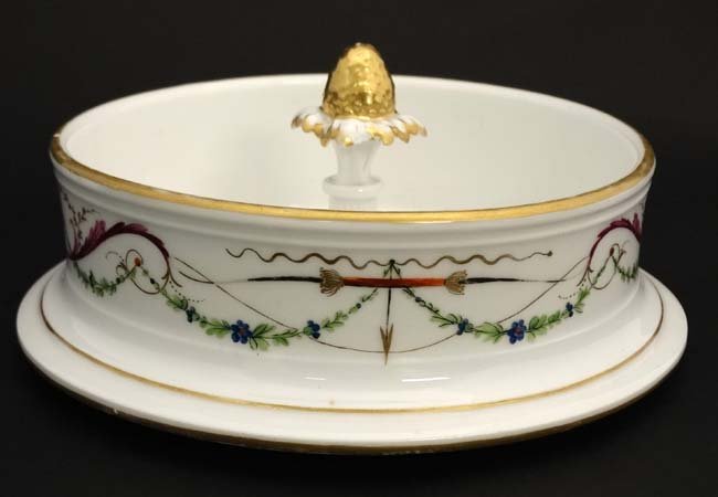 A 19thC Rockingham China style serving dish with: A 19thC Rockingham China style serving dish / ice pail cover with central knop formed as a gilded pineapple, the rim with stylised bow and arrow decoration and gilt highlights.