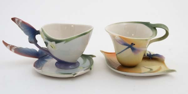 A Franz porcelain 'Dragonfly' pattern cup and saucer: A Franz porcelain 'Dragonfly' pattern cup and saucer set, number FZ0028, decorated with dragonflies on an orange ground , together with a Franz porcelain 'Butterfly' pattern cup and saucer set , decor