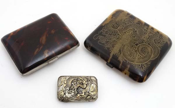 2 Japanese faux tortoiseshell cigarette cases together: 2 Japanese faux tortoiseshell cigarette cases together with a white metal vesta case with traces of gilding and decorated with stylised dragon. The largest 3 1/2'' high (3)
