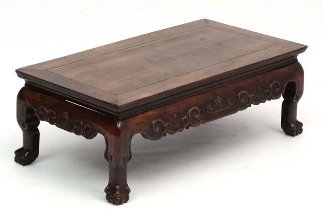 A late 19th Century Chinese hardwood low Table with: A late 19th Century Chinese hardwood low Table with scrolled decoration to the frieze on squat cabriole legs with claw terminals measuring 30 1/2'' long x 16 1/4 wide x 11'' high.