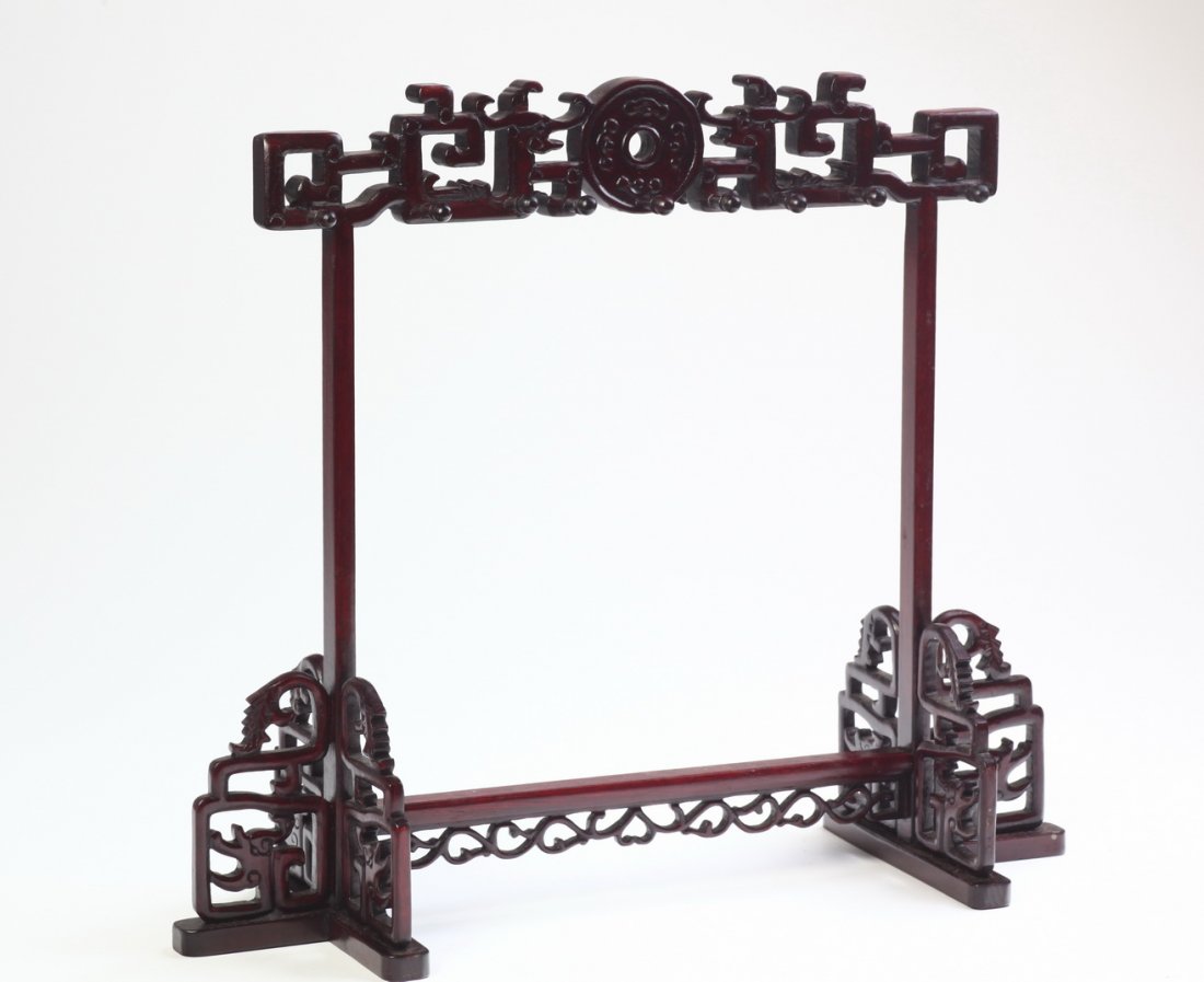 A Hardwood Ink Brush Hanger, 19 th Century 19ä¸–ç´€: 19 with nine hangers, the brush hanger carved with a Chinese traditional corn in the centre and scrolling vines, supported with two carved and pierced " T" legs. Dimensions: 35cm X 43cm