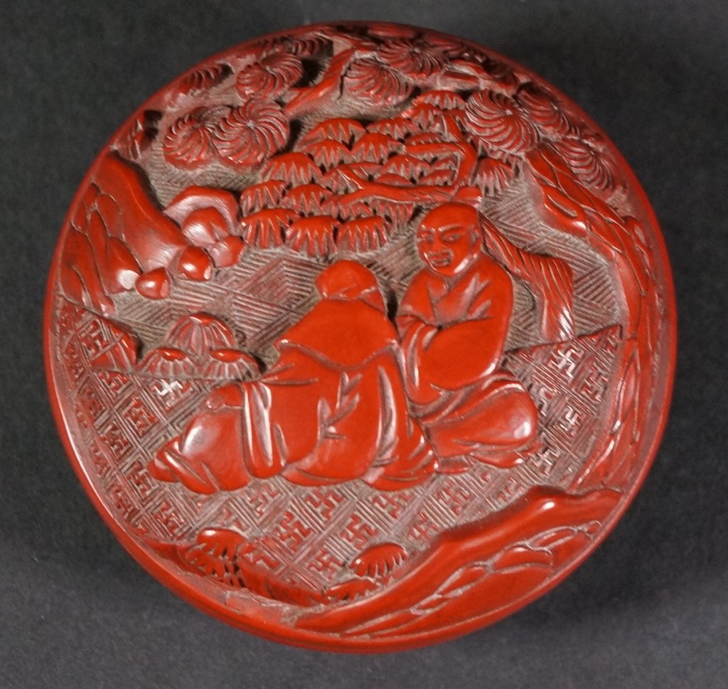 Chinese Double Sided Cinnabar Box: Of lead body, thick layer of cinnabar carved with scholar in garden scene. 18th century. Measures 3" in diameter.