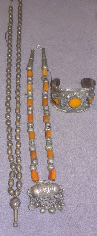 Three pieces of antique ethnic jewelry: Three pieces of antique ethnic jewelry. Afghan silver and amber necklace with bullet form pendant box, ..an excavated silver bead necklace, untouched surface, both quite ancient, and an old wide band
