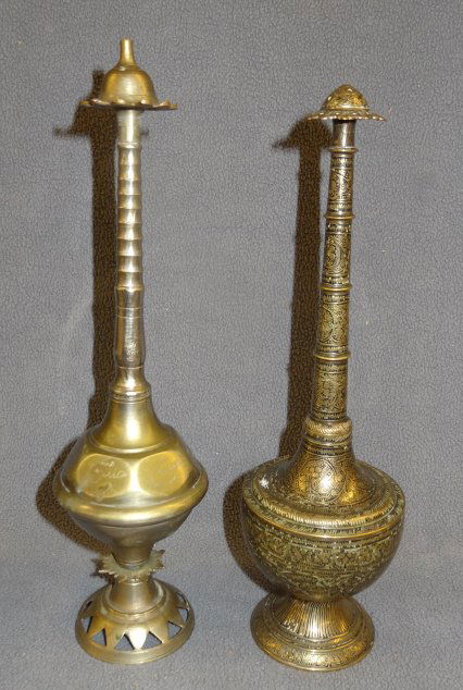 Two antique Islamic bronze sprinkler bottles: Two antique Islamic bronze sprinkler bottles. The simple one with pierced face, a paneled bottle, ring necked, 11" . The other finely engraved designs allover, the background filled with black enamel.