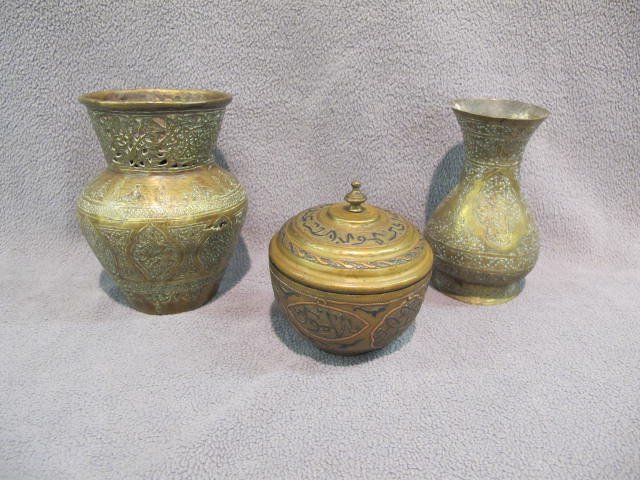 3 pc brass/bronze vessels: Three antique engraved Islamic inlaid or hammered brass/bronze vessels. All with extensive Kufic or Nashqi script. The larger probably 17C with pierced and cut gallery, stylized animals, etc. 5 1/2".