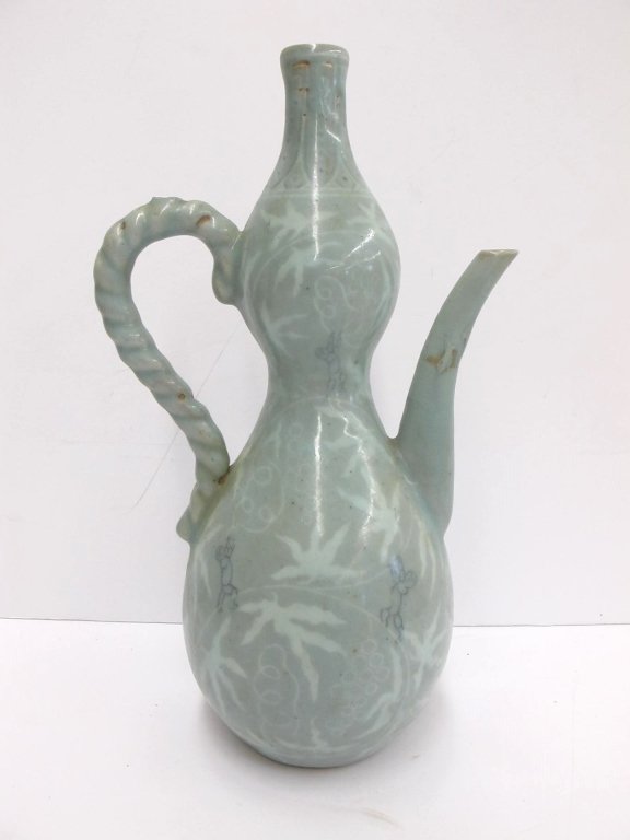 Early Korean inlaid celedon ewer: Early Korean inlaid celedon ewer. Yi dynasty, with old professional restoration on the spout, and a loop missing at the top of the handle. Young boys playing amongst leafy ground.