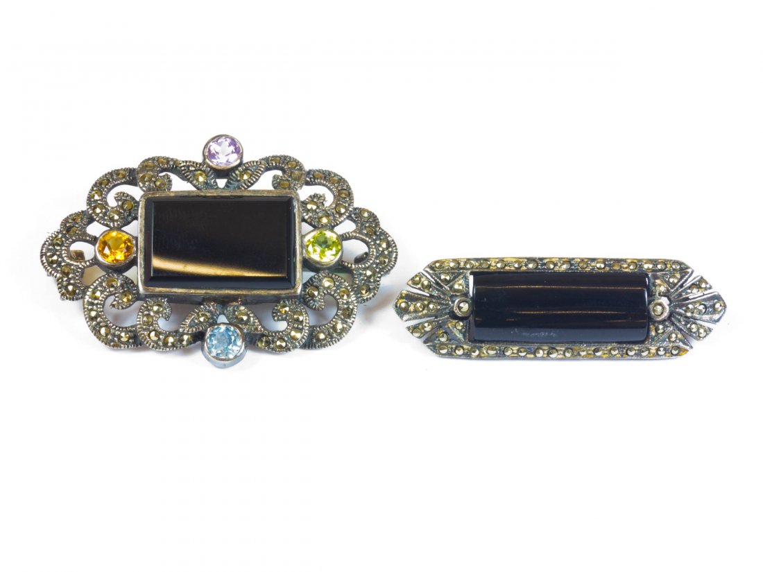 2 Silber-Onyx-Broschen, je 835/000 Silber, Markas: 2 silver onyx brooches, each 835/000 silver, marcasite braiding, Millegriffes-Decor: 1) narrow rectangular brooch, length 4.5 cm 2) rectangular brooch, pierced with scrolls, set with four transparent 