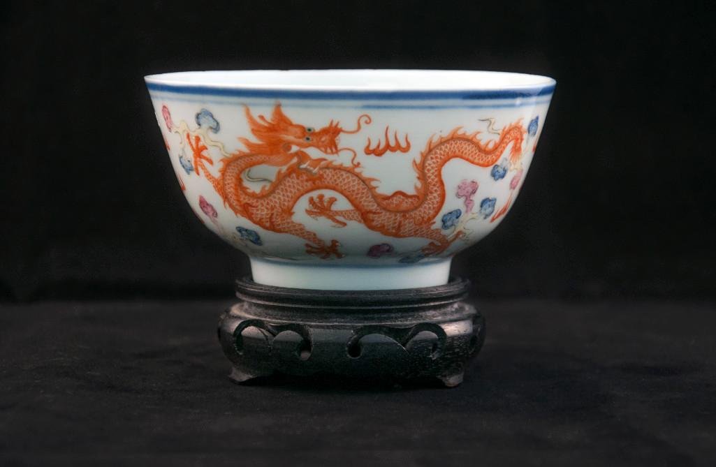 A DUCAI BOWL OF DRAGONS AND BATS: Painted with iron-red and green dragons racing amidst stems in pursuit of flames, the interior decorated with five bats with Shou character, GuangXu seal Mark. Height: 2 1/2in (6.5cm), Hiameter: 4 1/2
