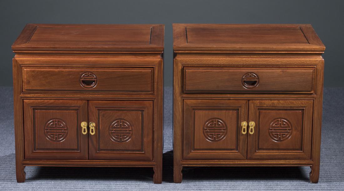 Pair of Chinese Carved Nightstands, 20th c.: A pair of Chinese carved nightstands, 20th century. Far East Furniture Company. Rosewood. Traditional square top over waist with one drawer over a two-door cabinet with brass pulls and carved shou sym