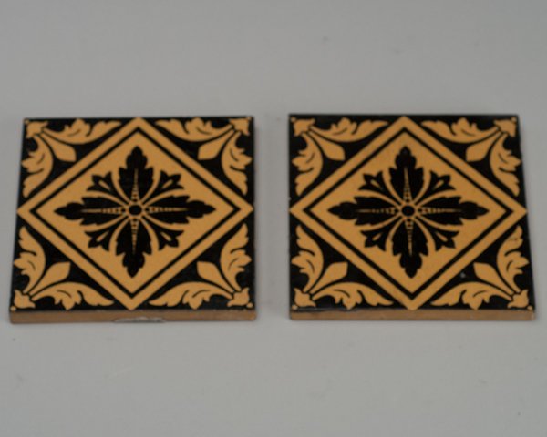 A Pair of Minton Black and Tan Tiles,: A Pair of Minton Black and Tan Tiles, marked on back Minton, Hollins & Co; Patent Tile Works Stoke On Trent No 2 B. Light scratching and small glaze losses at edges. Chip to back corner of one tile. E