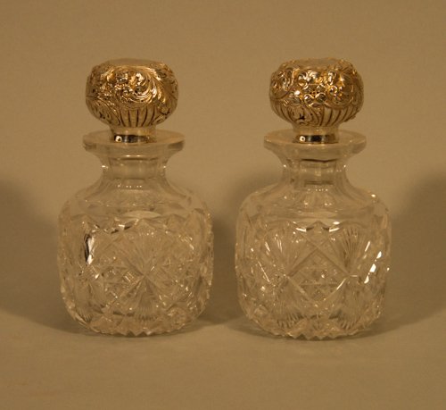 Pair of Old Cut Glass Bottles with Sterling Capped: Pair of Old Cut Glass Bottles with Sterling Capped Stoppers One bottle with chip to rim. Height: 5 3/4"" Diameter: 3 1/2""