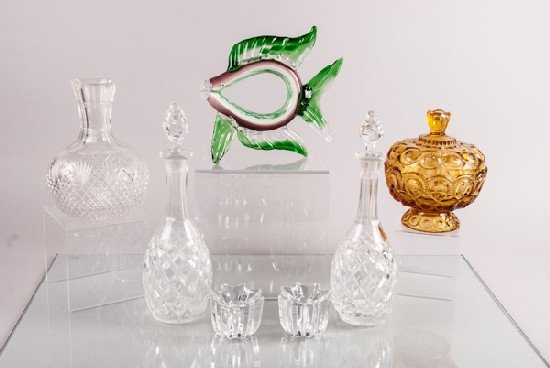 Lot of Glassware: Lot of Glassware To include (eight pieces): two (2) colored pieces of glass, pair of Orrefors glass candlesticks, Murano glass fish, two (2) decanters, cut glass vase. 10"" H
